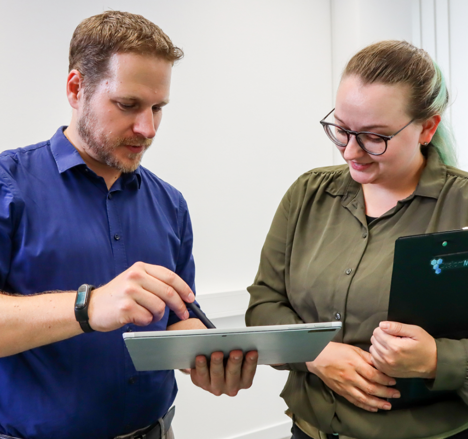 Two employees in front of a tablet.