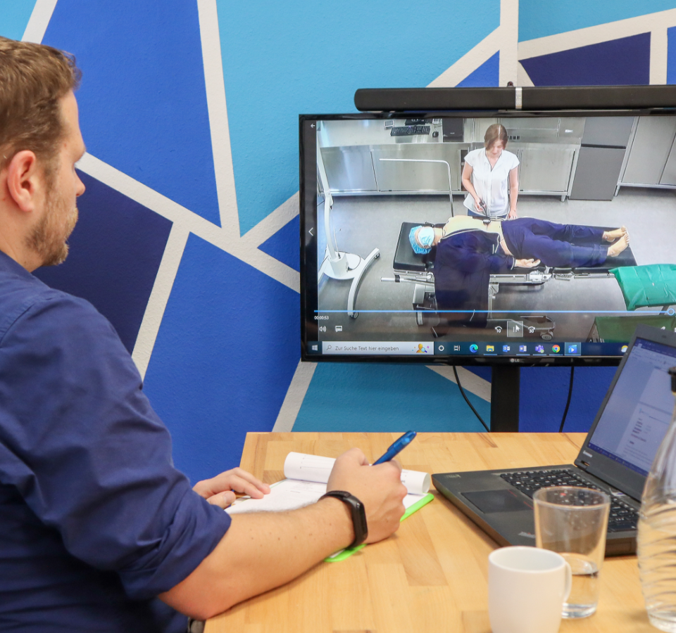 An employee observes a UX test on a screen from an observation room.