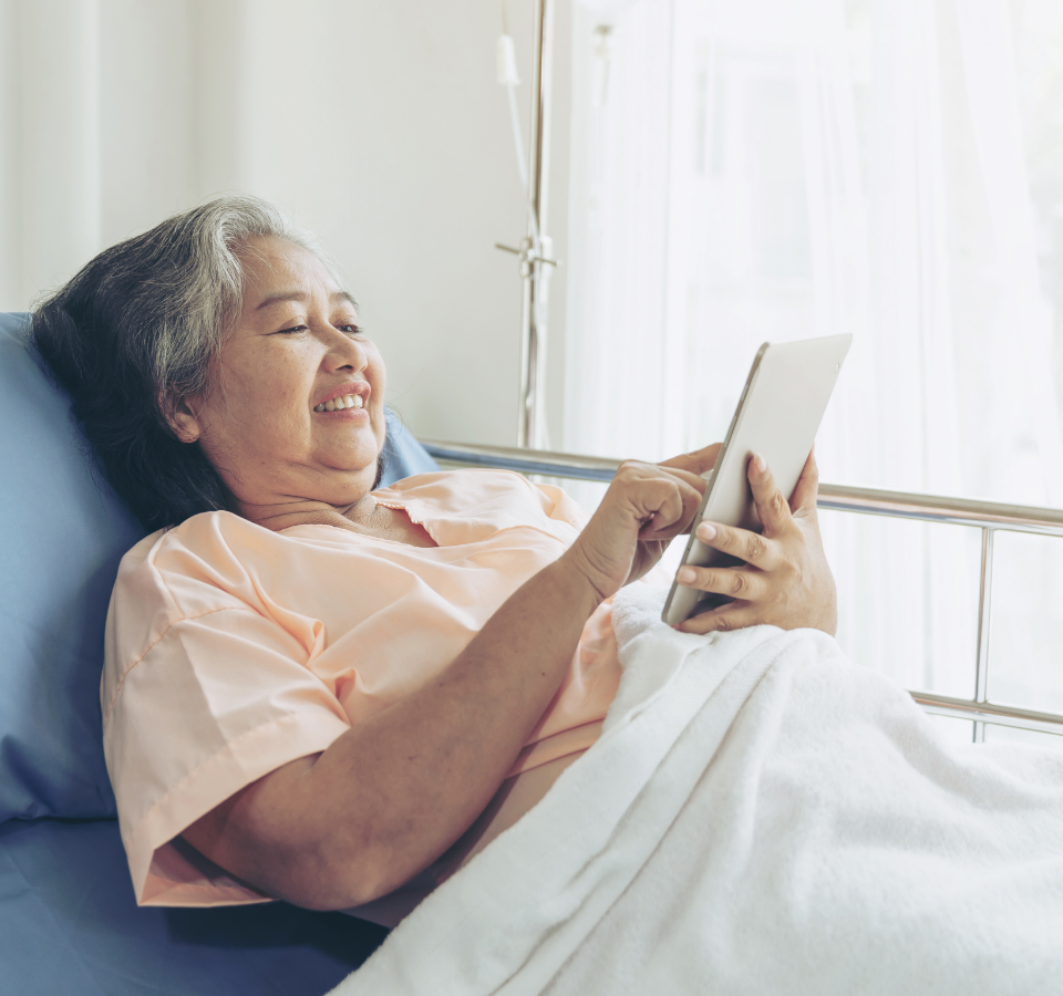 A woman uses a tablet in bed.