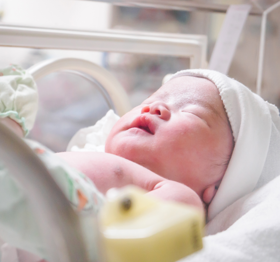 Ein Neugeborenes in einem Inkubator.